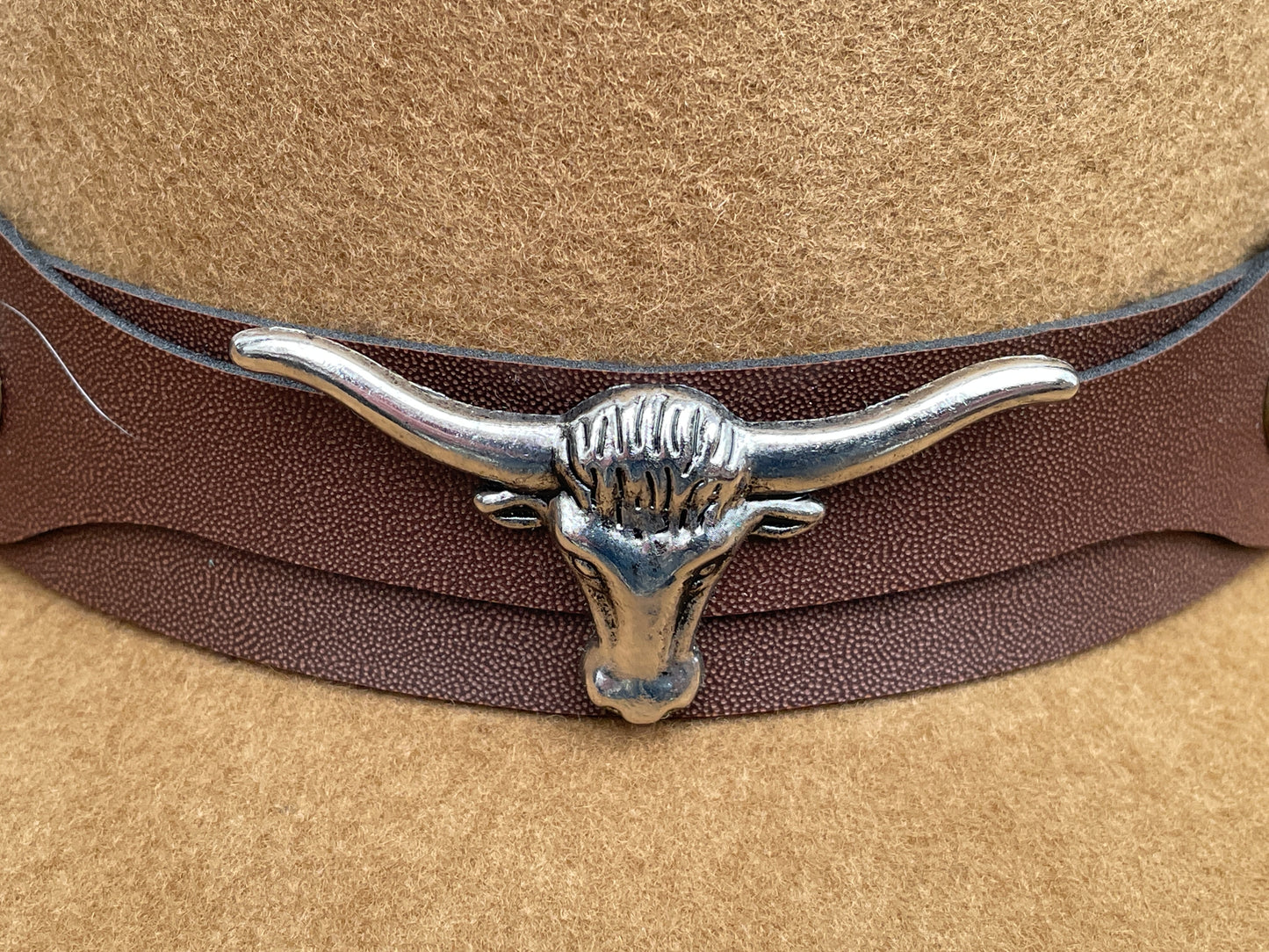 Brown cowboy hat made of high-quality felt with leather band and metal bull head