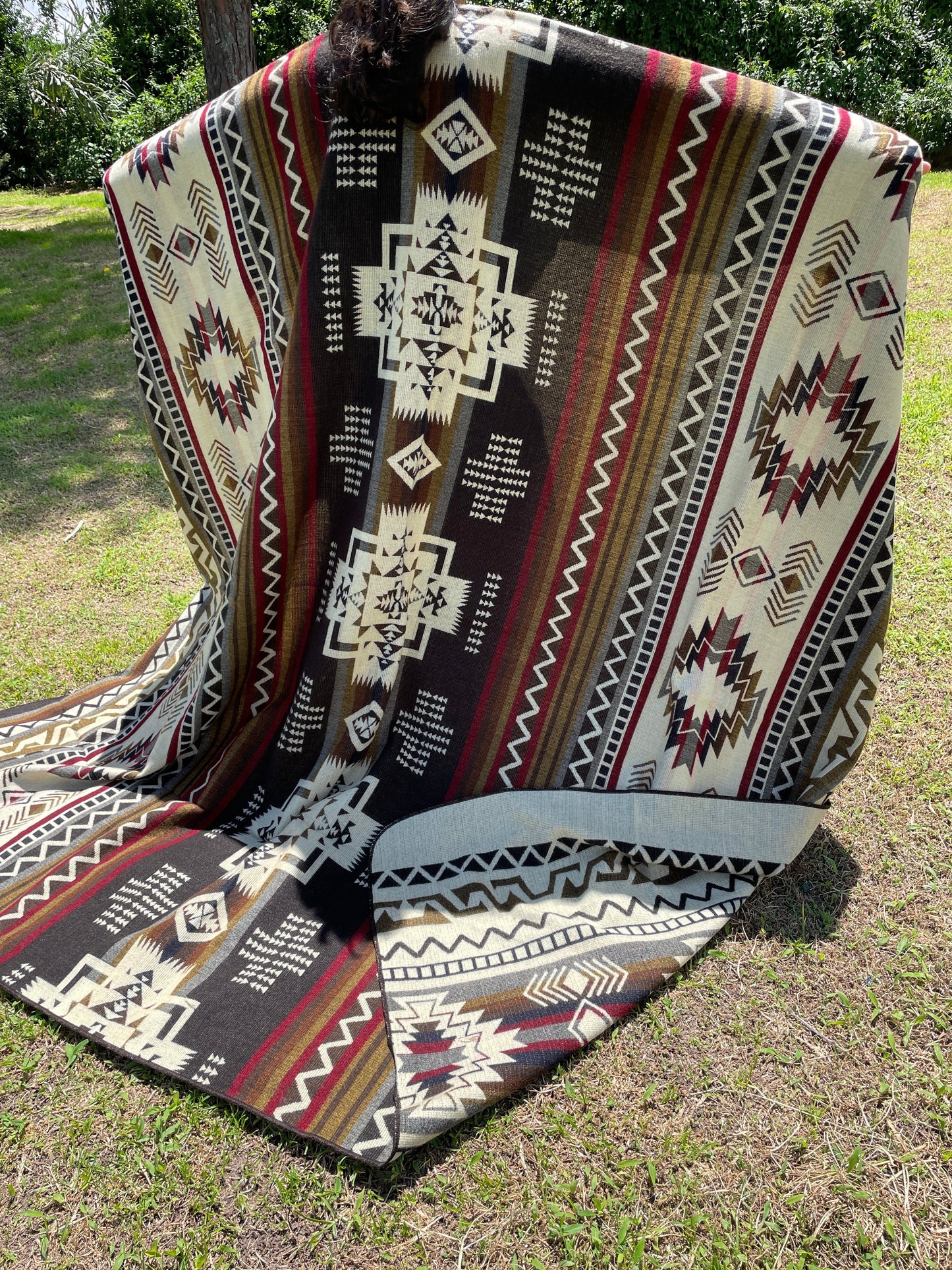 TomHats brown alpaca blanket featuring traditional indigenous geometric patterns, handmade and displayed outdoors.