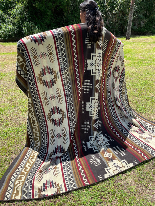 TomHats brown alpaca blanket featuring traditional indigenous geometric patterns, handmade and displayed outdoors.