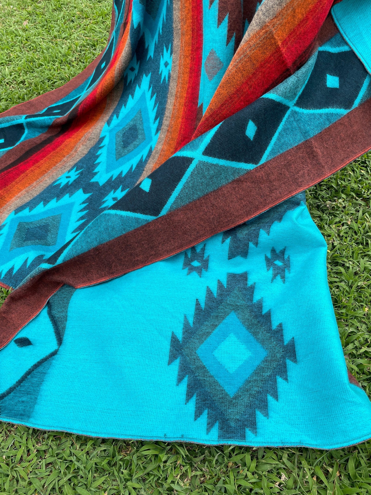 TomHats alpaca wool blanket in turquoise and brown with traditional Navajo patterns for cozy evenings on the sofa.