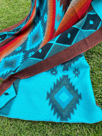 TomHats alpaca wool blanket in turquoise and brown with traditional Navajo patterns for cozy evenings on the sofa.