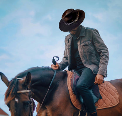 TomHats Havana black wool felt Boater Outback hat, worn by a man on horseback outdoors.