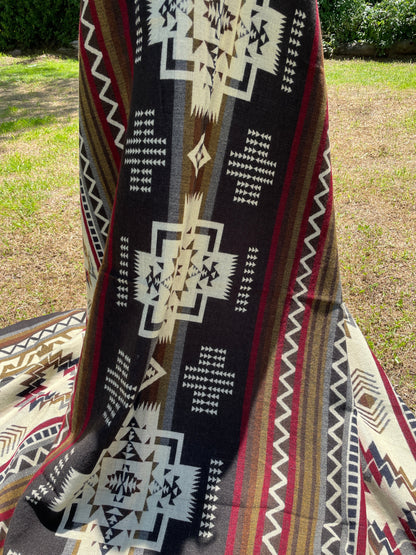 TomHats brown alpaca blanket featuring traditional indigenous geometric patterns, handmade and displayed outdoors.